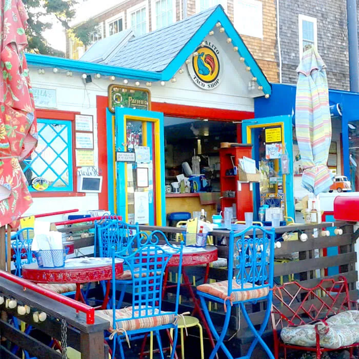 Colorful Sausalito taco shop exterior with bright blue and red patio chairs