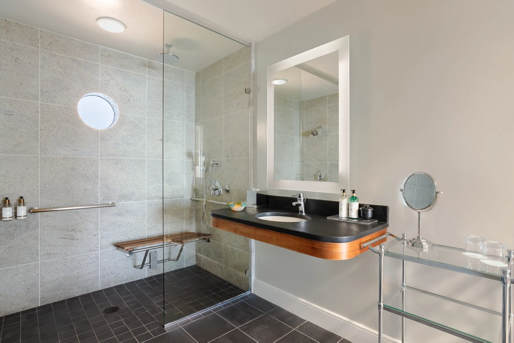 Guest bathroom with walk-in glass shower, teak bench and floating vanity