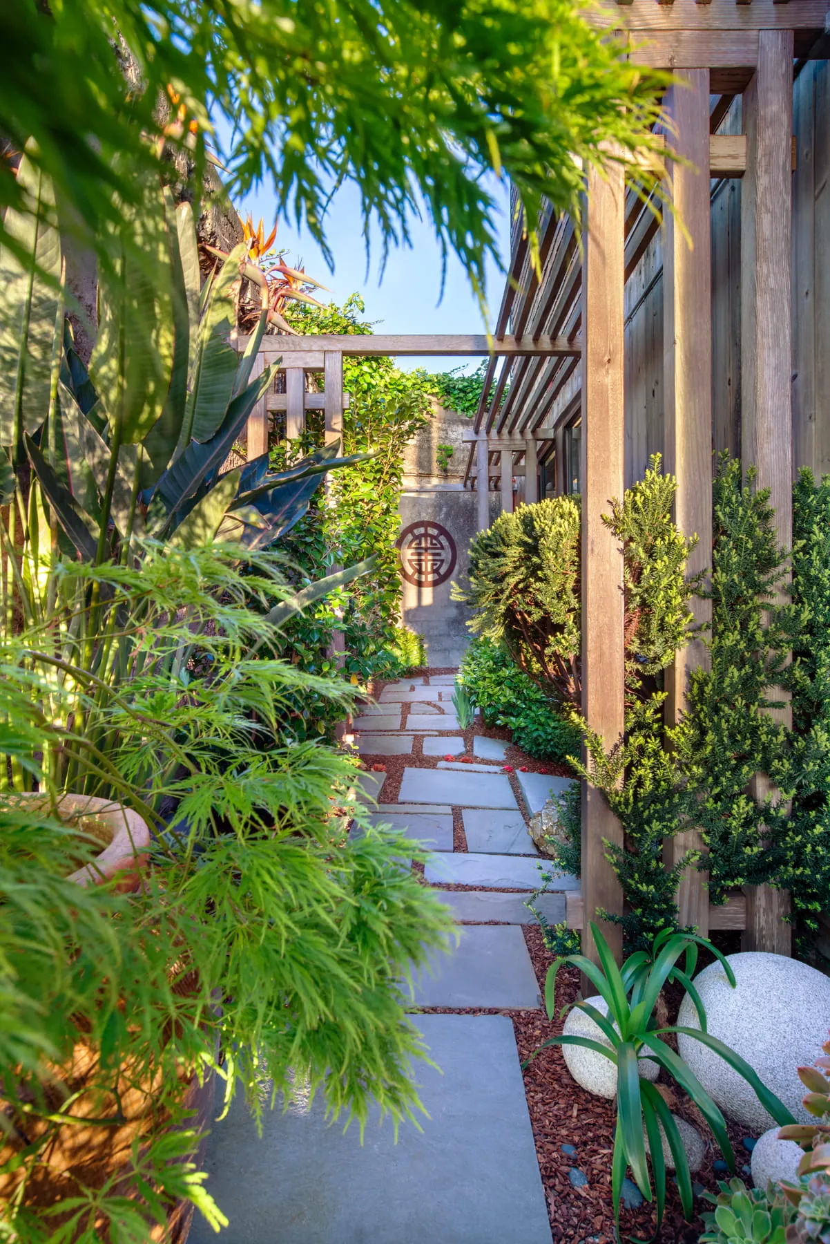 Lush garden path with flagstone walkway, tropical plants, and wooden trellis