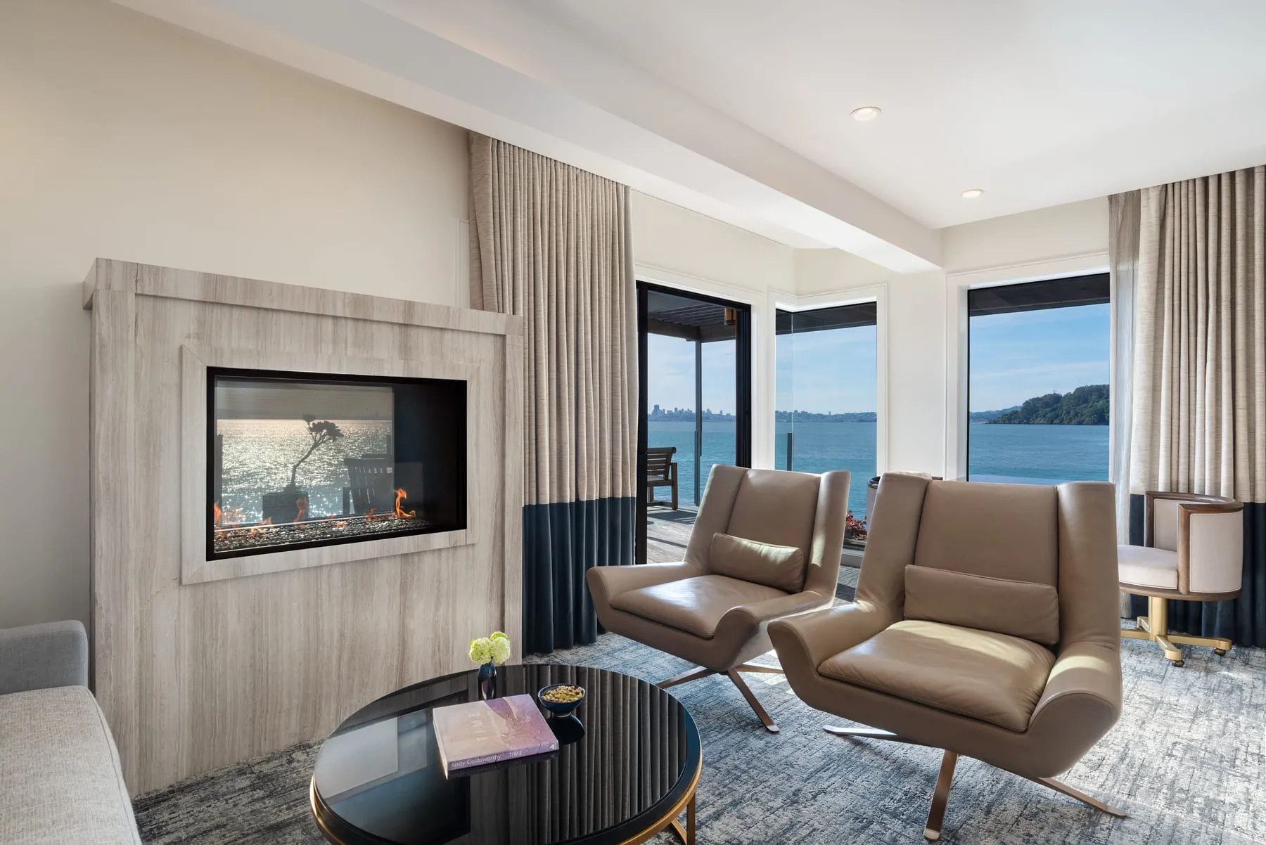Suite sitting area at this Sausalito hotel with fireplace, leather chairs and floor-to-ceiling bay views