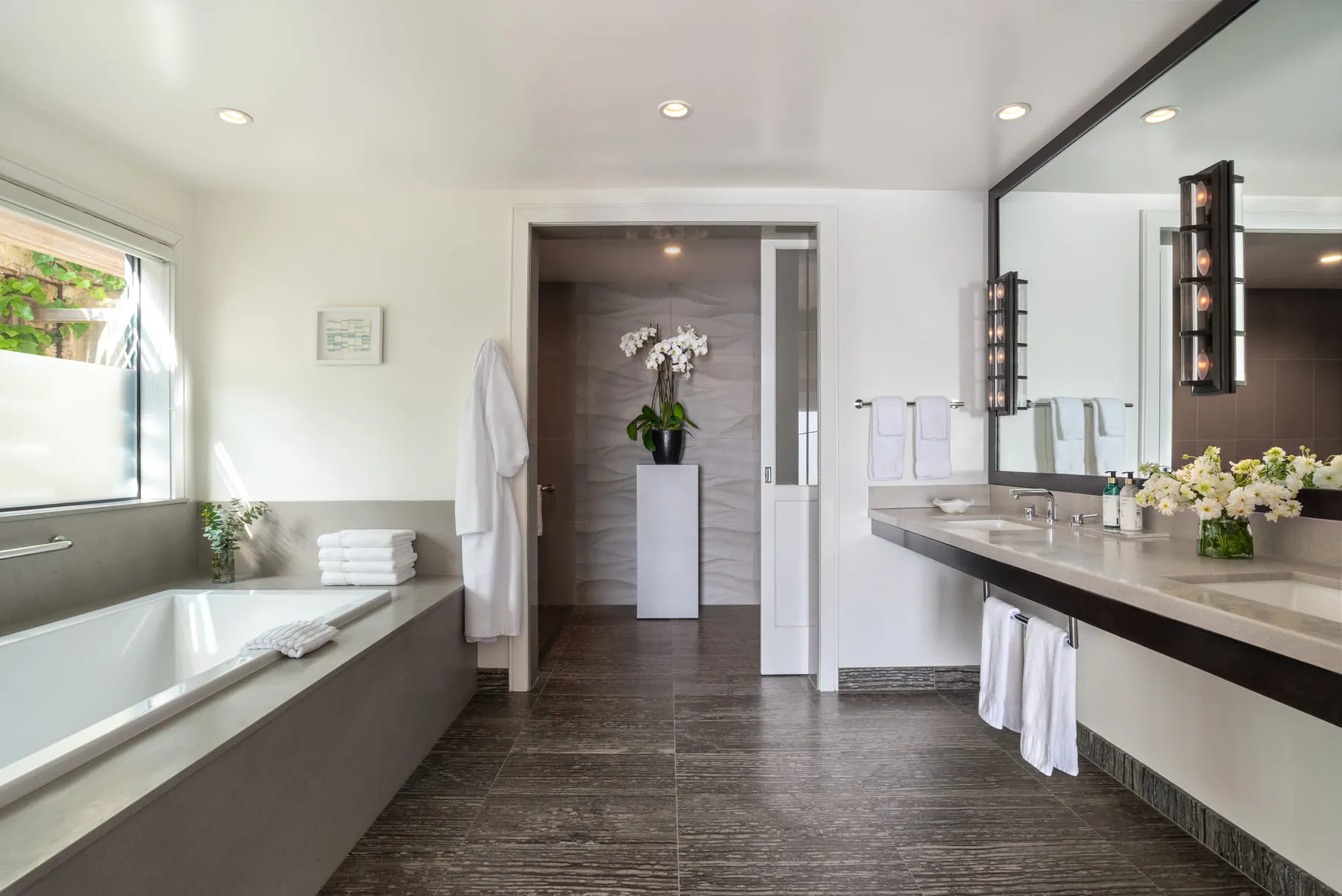 Luxury bathroom with soaking tub, double vanity, and orchid display