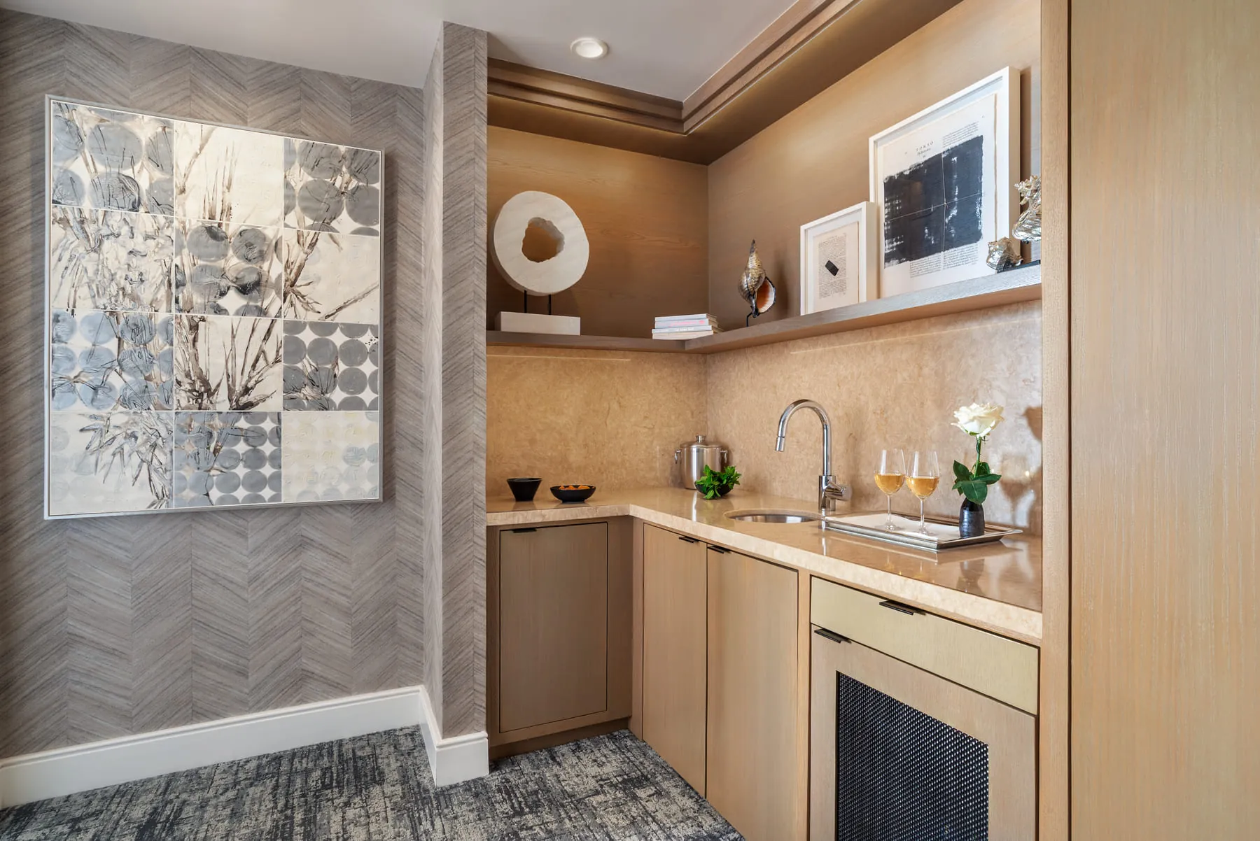 Suite wet bar with sink, wine glasses, and framed art on patterned wall